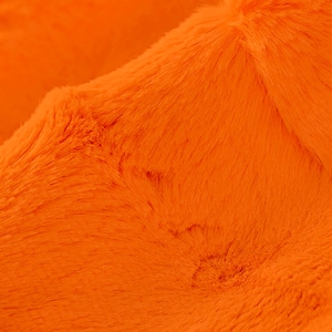 May include: Close-up of a bright orange faux fur fabric. The fabric has a soft, plush texture.