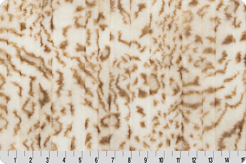 Pu&ograve; includere: Tessuto in pelliccia sintetica bianca con strisce marroni. Il tessuto ha una texture morbida e soffice.