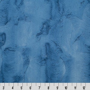 May include: A close-up of a soft, blue fabric with a fuzzy texture. The fabric has a subtle, mottled appearance, creating a unique and interesting visual effect.
