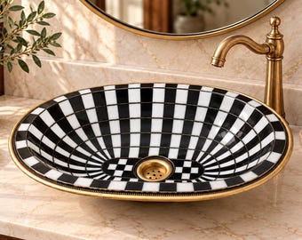 May include: An oval bathroom sink featuring a black and white checkered pattern across its interior surface. The basin is framed by a metallic gold rim and includes a matching gold-toned drain fixture centered at the bottom of the vessel.