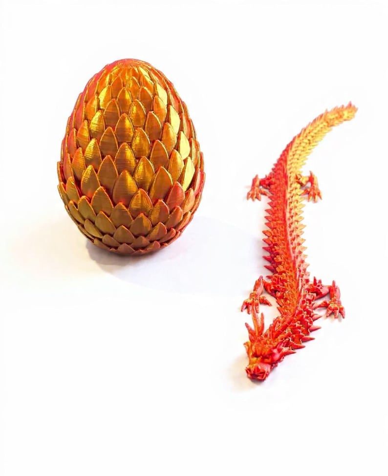 May include: A golden-orange, textured dragon egg and a red and orange dragon figurine. The egg is oval-shaped and made of overlapping, scale-like segments. The dragon is detailed with a spiky spine and outstretched limbs, and is lying down.