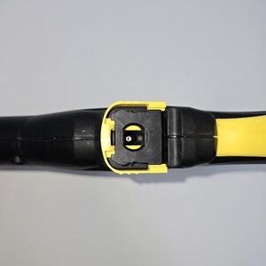 May include: A black and yellow pressure washer wand. The wand features a yellow trigger and nozzle area, with a black handle and body. The image is a close-up shot of the wand, highlighting its design and construction.