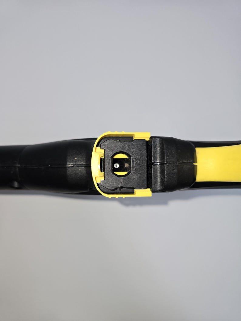 May include: A black and yellow pressure washer wand. The wand features a yellow trigger and nozzle area, with a black handle and body. The image is a close-up shot of the wand, highlighting its design and construction.