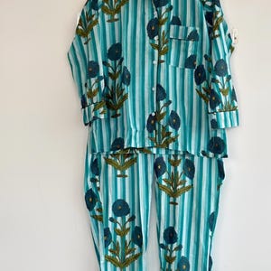 May include: A white ceramic mug with a black handle and the text "But First, Coffee" in a bold, black font. The mug is set against a blurred background, suggesting a cozy setting.