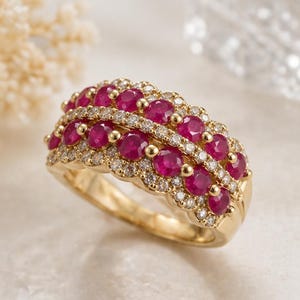 May include: A gold ring featuring rows of vibrant red rubies and sparkling diamonds. The ring's design includes a scalloped edge and small gold accents, creating a luxurious and eye-catching piece of jewelry.