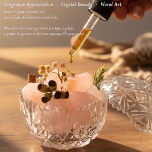 May include: A clear, faceted glass bowl filled with pink crystals, dried flowers, and decorative elements. A dropper dispenses essential oil. Text reads "Fragrance Appreciation," "Crystal Beauty," and "Floral Art."