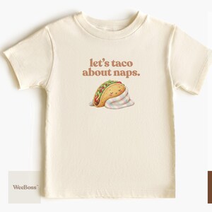 A cute taco character wrapped in a striped blanket, pastel colors - detailed view of a natural toddler t-shirt with product feature highlights - exclusive WeeBoss print detail