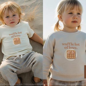 A cute, hand drawn waffle with heart toppings in soft colors - lifestyle image of a young girl wearing a natural heather toddler sweatshirt in a scenic outdoor desert setting - exclusive WeeBoss print detail