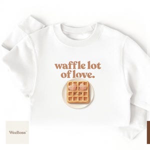A cute, hand drawn waffle with heart toppings in soft colors - detailed view of a white toddler t-shirt with product feature highlights - exclusive WeeBoss print detail