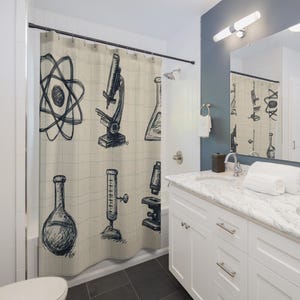 May include: A beige shower curtain featuring a scientific theme with hand-drawn illustrations. The design includes an atom model, a microscope, beakers, and other lab equipment in a dark blue color. The curtain is hanging in a bathroom setting.