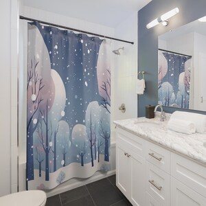 Könnte beinhalten: Ein blauer Duschvorhang mit einer Winterwaldszene. Das Design zeigt stilisierte Bäume in Blau- und Lilatönen mit fallendem Schnee und einem großen, blassen Mond. Der Vorhang hängt in einem Badezimmer mit weißen Schränken und einer Marmorarbeitsplatte.