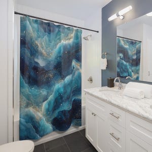 May include: A blue and gold abstract shower curtain with a watercolor effect. The design features swirling shades of blue, teal, and gold, creating a dreamy, cloud-like pattern. The curtain hangs in a bathroom setting.