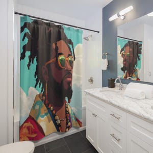 May include: A shower curtain featuring a stylized portrait of a person with dark skin, wearing orange-tinted sunglasses and jewelry. The background is a light blue sky with white clouds. The person has long black hair and a beard. The curtain is hanging in a bathroom.