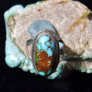 K&ouml;nnte beinhalten: Ein silberner Ring mit einem T&uuml;rkis-Stein, der in einer Zargenfassung gefasst ist. Der Stein ist in einem gefleckten Blau und Gr&uuml;n mit braunen Adern.