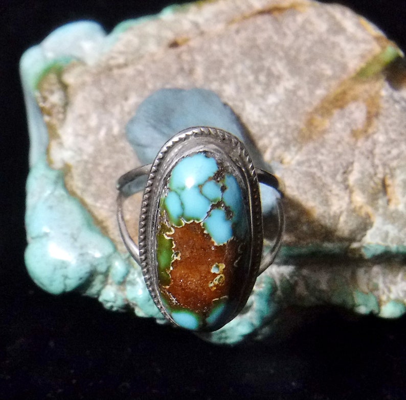 K&ouml;nnte beinhalten: Ein silberner Ring mit einem T&uuml;rkis-Stein, der in einer Zargenfassung gefasst ist. Der Stein ist in einem gefleckten Blau und Gr&uuml;n mit braunen Adern.