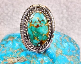 May include: A silver ring featuring a turquoise stone set in an oval bezel. The stone has a green and brown marbled pattern.