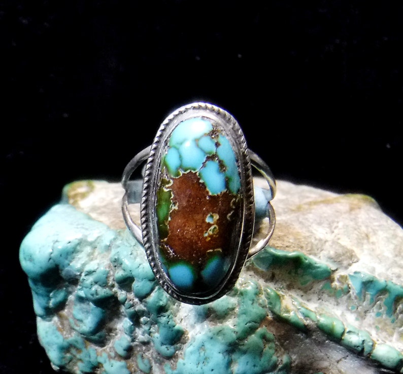 K&ouml;nnte beinhalten: Ein silberner Ring mit einem ovalen T&uuml;rkis-Stein, der in einer Zargenfassung sitzt. Der T&uuml;rkis hat eine leuchtende blaugr&uuml;ne Farbe mit brauner Matrix.