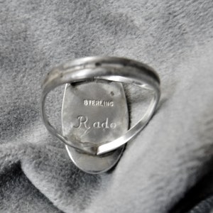 K&ouml;nnte beinhalten: Ein silberner Ring mit einem ovalen Stein. Die R&uuml;ckseite des Rings ist mit "STERLING" und "Rado" graviert.