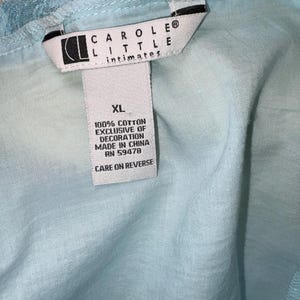 May include: A light blue garment with a lace trim. The tag reads "CAROLE LITTLE intimates" and "XL". The tag also states "100% COTTON EXCLUSIVE OF DECORATION MADE IN CHINA RN 59478 CARE ON REVERSE".
