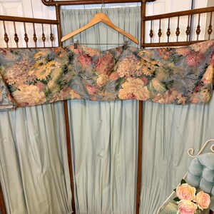 Puede incluir: Una cenefa floral vintage con fondo azul y marco de madera. La cenefa presenta grandes flores coloridas en tonos rosa, amarillo y crema. El marco es de madera oscura y tiene un dise&ntilde;o decorativo en la parte superior.