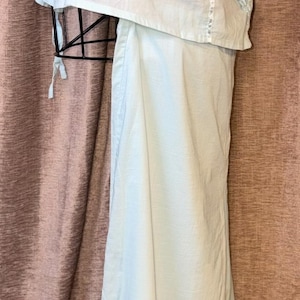 May include: A light blue vintage lingerie set, including a camisole and matching pants. The camisole features delicate lace trim along the neckline and straps. The pants have a ruffled hem. The set is displayed on a black mannequin.