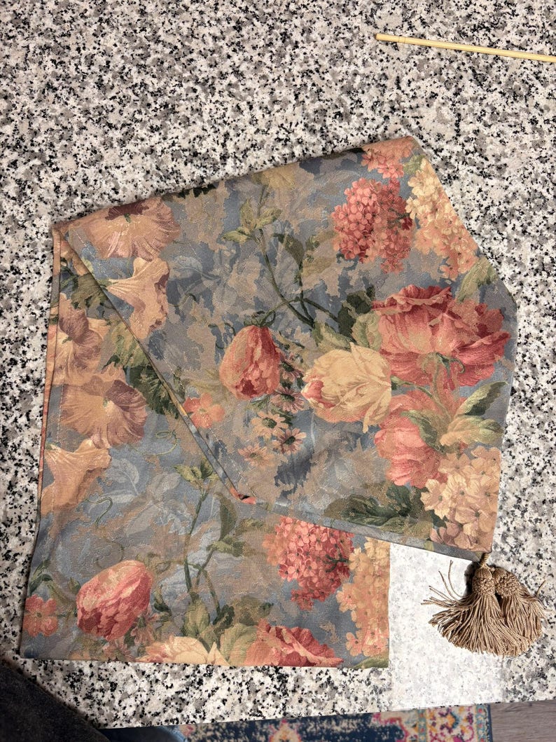 Puede incluir: Tela estampada con motivos florales en tonos azules, melocot&oacute;n y amarillo. El dise&ntilde;o presenta flores y hojas detalladas. Se adjunta una borla a juego. Ideal para la decoraci&oacute;n del hogar.