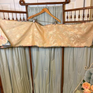 Puede incluir: Un biombo de madera vintage con un fondo de tela azul claro. Una tela estampada est&aacute; drapeada sobre la parte superior, sujeta por una percha de madera. El biombo tiene un dise&ntilde;o decorativo y ornamentado.