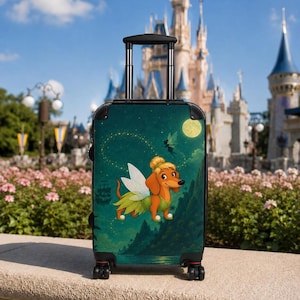 May include: A rolling suitcase featuring a graphic of a brown dachshund wearing a green fairy outfit with wings. The background shows a dark green landscape with a full moon, a silhouette of a ship, and a small fairy figure flying in the night sky.