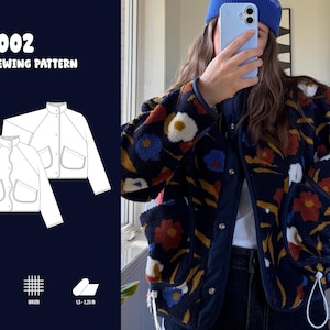 Puede incluir: Un patrón de costura en PDF etiquetado como JK002 que presenta un dibujo técnico de una chaqueta con cuello alto, cierres a presión y dos bolsillos delanteros. La chaqueta es de tejido polar azul marino oscuro con estampado floral.