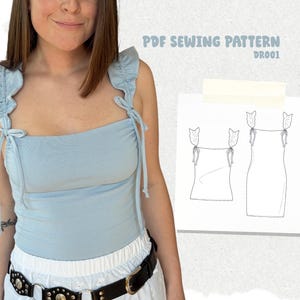 Peut inclure: Un haut bleu clair avec des bretelles à volants et des liens. Le haut est associé à une jupe blanche et une ceinture noire. Un patron de couture PDF est visible avec le texte "PDF SEWING PATTERN DR001".