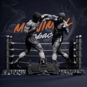 May include: A detailed sculpture of two boxers in a ring, one throwing a punch. The sculpture is dark gray with black gloves and shorts. The text "M JIM" and "space" is visible in the background. The base reads "Rocky Balboa" and "Apollo Creed."