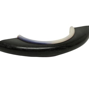May include: Black ceramic door handle with a white and blue inlay. The handle is curved and has a smooth finish.