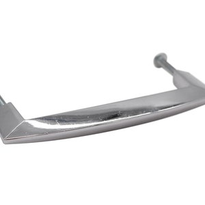 May include: A silver-toned, rectangular cabinet pull with rounded edges and a slight curve. The pull has two screw holes on the underside.