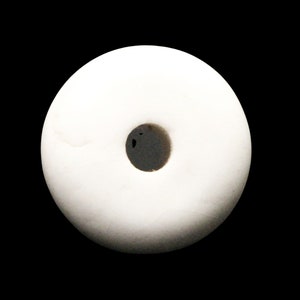 May include: A white ceramic donut bead with a hole in the center. The bead is smooth and has a glossy finish.