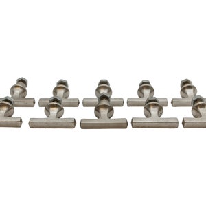 Könnte beinhalten: Acht silberfarbene T-förmige Schrankknöpfe mit einem runden Knopf oben. Die Knöpfe haben eine leicht strukturierte Oberfläche.