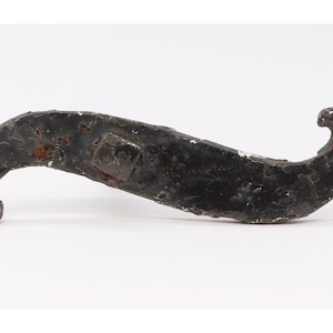 May include: A black metal wrench with a curved handle and a square head. The wrench is rusty in places.