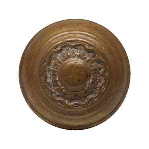 Peut inclure: Une poignée de porte ronde en laiton avec un motif circulaire décoratif en relief au centre.