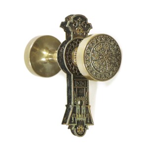 Puede incluir: Un pomo de puerta de latón vintage con un diseño ornamentado. El pomo presenta un patrón circular detallado y una cerradura.
