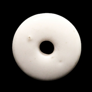 May include: White ceramic donut-shaped bead with a hole in the center.