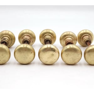 May include: Ten antique brass door knobs. The knobs are round with a polished finish and a warm, golden color. The stems are a darker bronze color. The knobs are arranged in two rows of five.