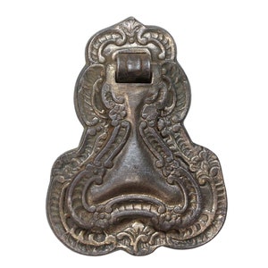 May include: An ornate, antique-looking metal drawer pull with a detailed, intricate design. The pull is a dark, aged silver color and has a slightly tarnished finish.
