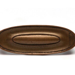 May include: A bronze oval-shaped door pull with a raised, slightly smaller oval in the center.
