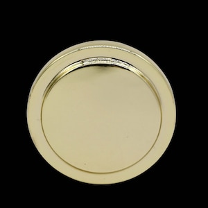 Pode incluir: Uma tampa de garrafa redonda de cor dourada com uma superfície lisa e brilhante.