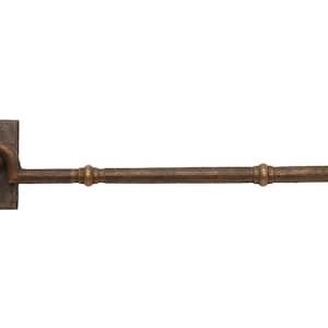 May include: A bronze-coloured window or door hook and eye latch. The latch has a rectangular base with a circular hole, a curved hook, and a straight bar with decorative rings. The end of the bar has a circular piece with a screw.