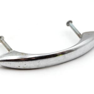 May include: A silver-toned metal handle with a curved design and two screw holes. The handle is slightly tarnished.