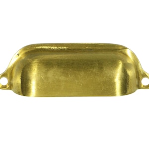 May include: A brass cabinet pull with a rounded rectangular shape and a smooth, brushed finish.