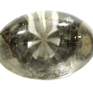 May include: A clear, oval-shaped glass paperweight with a starburst pattern in the center. The paperweight has a gray and brown marbled appearance.