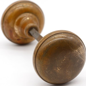 Peut inclure: Une poignée de porte en laiton vintage de forme ronde avec une finition légèrement usée.