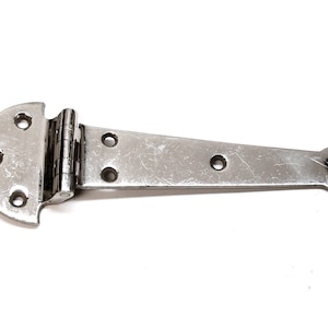 May include: A silver-toned metal hinge with a rounded end and multiple holes. The hinge is designed for attaching a door or gate to a frame.