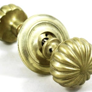 May include: A pair of antique brass door knobs with a fluted design. The knobs are attached to a round brass plate.
